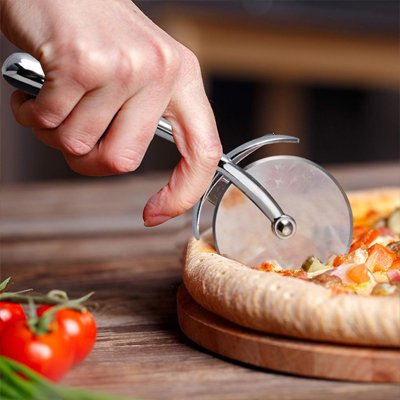 Couteau à pizza à coté d'une pizza 